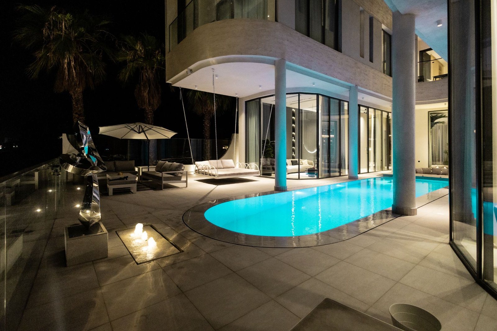 A private villa in Kuwait at night, with its pool and terrace lit