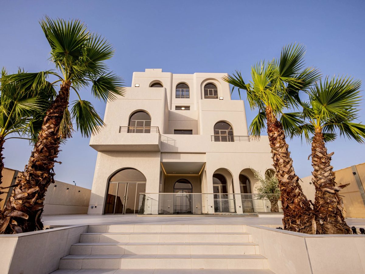 White villa with arches and palm trees in Sabah Al Ahmad Sea City
