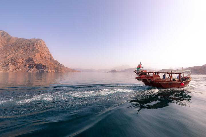 A wooden dhow sailing between the cliffs of Khor Ash Sham in Musandam