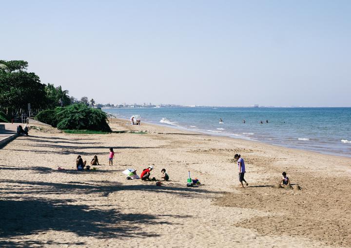 Qurum Beach in Muscat on a sunny day, families on the sand and the sea behind