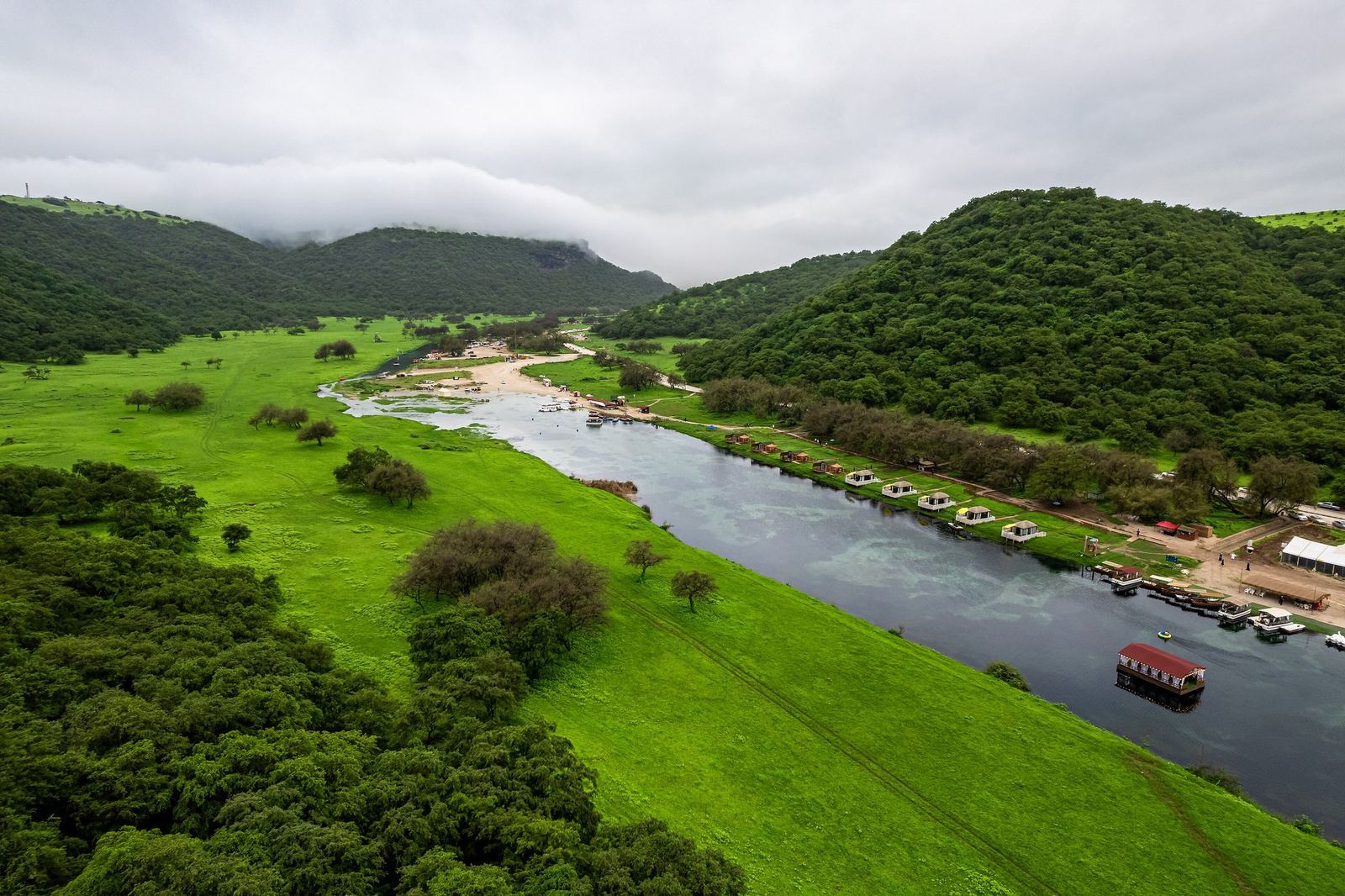 Green meadows and the lake of Wadi Darbat under monsoon cloud