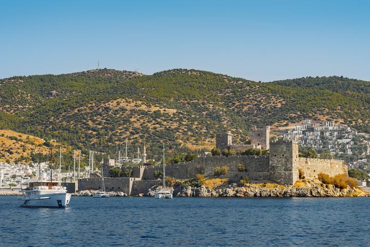 Bodrum Castle on the water with boats and white houses behind it