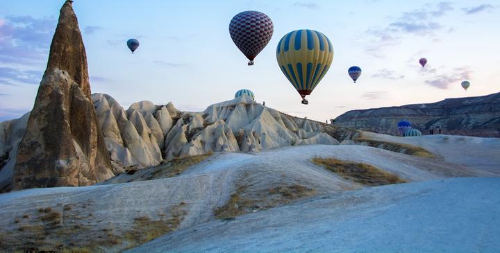 Hot air balloons drifting over fairy chimneys near Göreme at dawn, Cappadocia