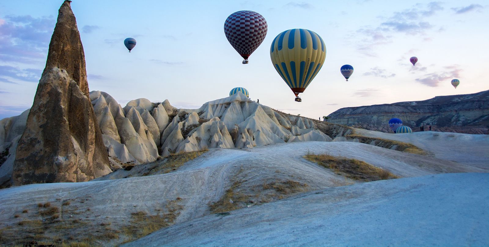 Hot air balloons drifting over fairy chimneys near Göreme at dawn, Cappadocia