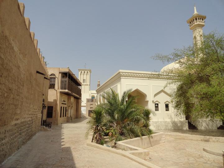 A lane in Al Fahidi with a wind tower and a white mosque