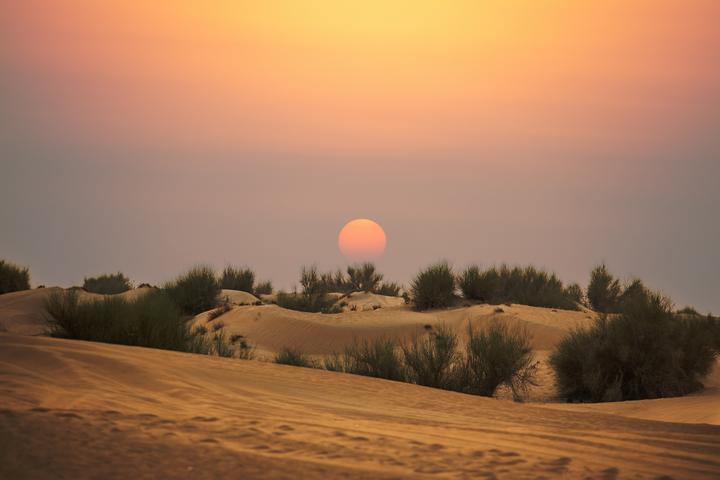 The sun setting over the dunes outside Dubai