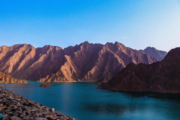 The turquoise lake of Hatta Dam between bare mountains