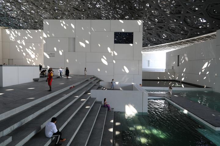 Light falling through the dome of Louvre Abu Dhabi onto white walls and water